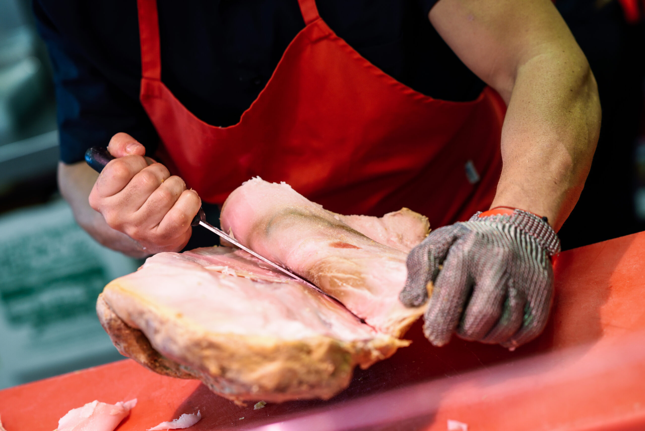 Butcher Boning A Ham In A Modern Butcher Shop